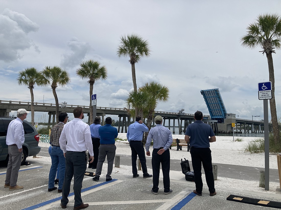 A drone flies over the Longboat Pass Bridge at an 80-foot elevation to contextualize what a fixed-span bridge would look live over the pass. Looking on (from left to right) are Longboat Key Commissioner Steve Branham, FDOT Southwest Area Office Director Wayne Gaither, FDOT Professional Engineer Trainee Stephen Pack, FDOT Project Manager David Turley, FDOT Project Development Manager Jimmy Vilce, FDOT Interim District One Secretary Jamie Driggers, Longboat Key Town Manager Howard Tipton and Longboat Key IT Director Jason Keen.