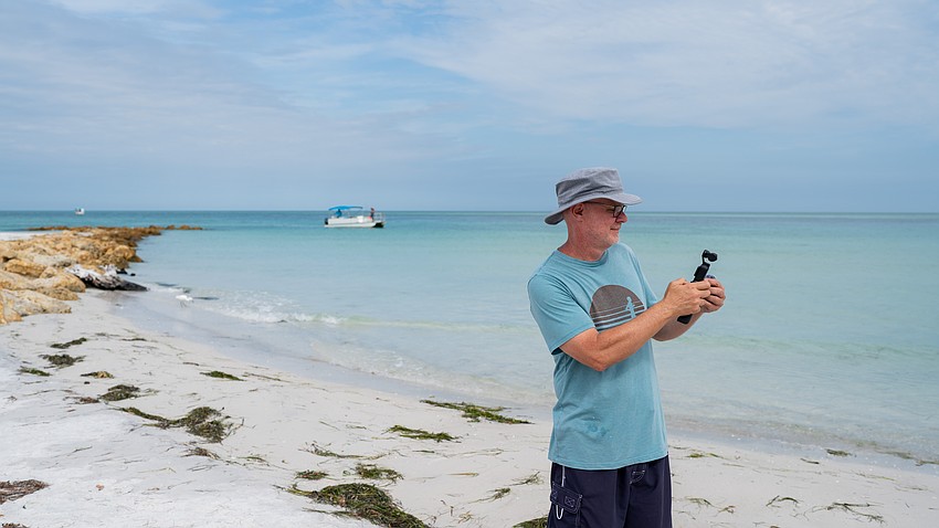 Shane Hammond films on Beer Can Island with his handheld video camera. Hammond said he appreciates the natural beauty of the beach and prefers when the driftwood has not been painted. Shane Hammond films on Beer Can Island with his handheld video camera. Hammond said he appreciates the natural beauty of the beach and prefers when the driftwood has not been painted.
