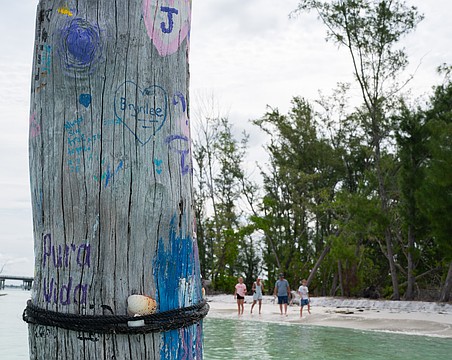 A piece of driftwood that juts from the shallow water off Beer Can Island is decorated with paint.