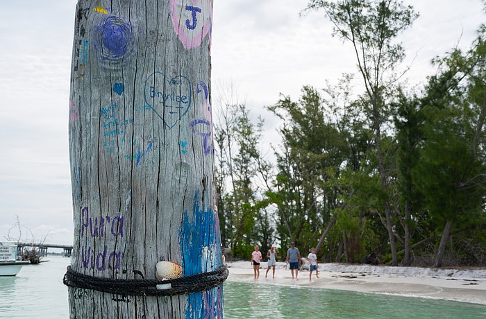 A piece of driftwood that juts from the shallow water off Beer Can Island is decorated with paint.