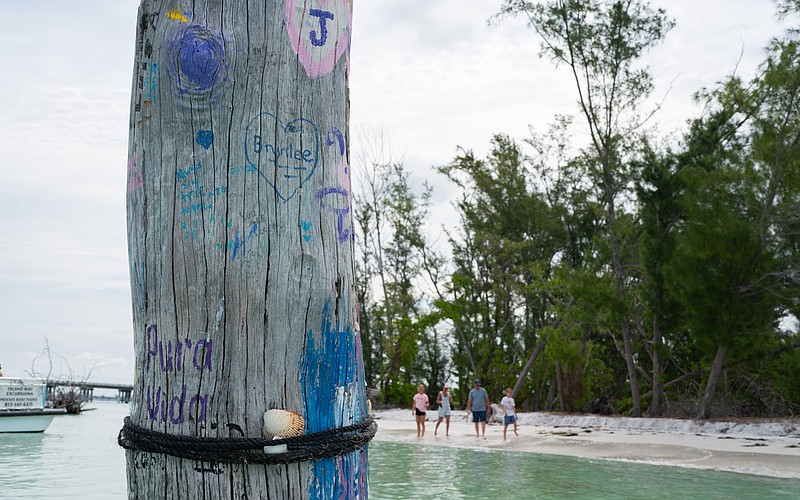A piece of driftwood that juts from the shallow water off Beer Can Island is decorated with paint.