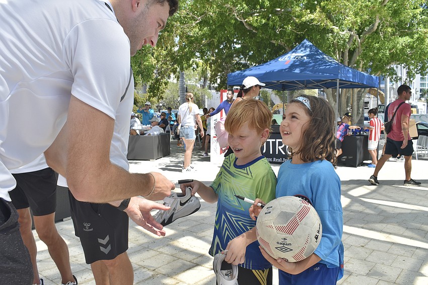 Declan Watters, centerback for Sarasota Paradise, signs shoes and a soccer ball for Roman Brenner, 7, and Berlin Fronczak, 7.
