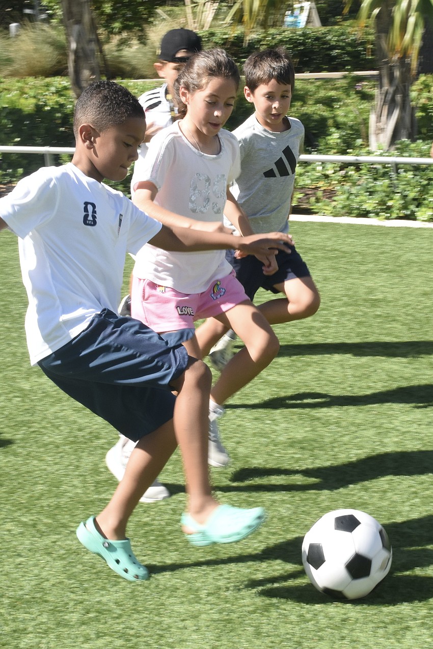 Enzo Gentry, 7, Olivia Escorcia, 9, and her brother Marcus Escorcia, 7, play on the green.