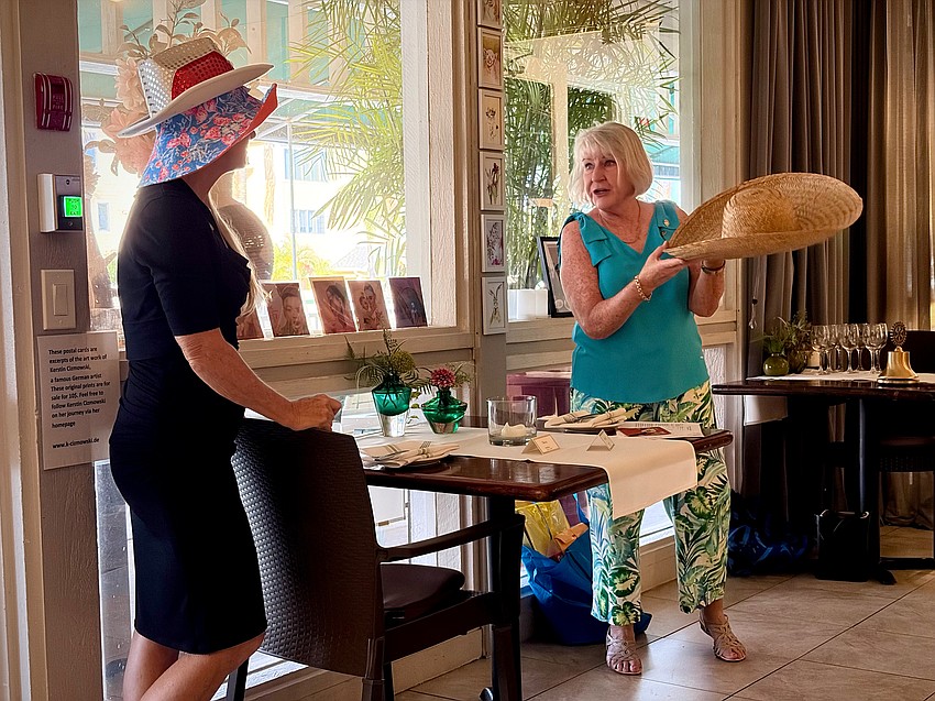 Rotary Club of Longboat Key member Carol Erker illustrates how hard returning President Terri Driver works to fill multiple roles with the club by presenting three immensely stylish hats for her to wear.