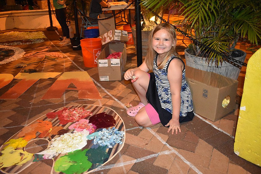 Scarletta Pirkle, 7, helps to place flower petals on the paint pad.