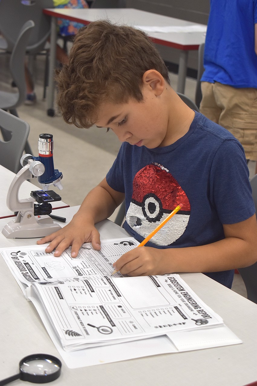Dylan Wallace, a rising fourth grader at Freedom Elementary School, looked through the microscope at sheep hair and makes sure to note he saw 