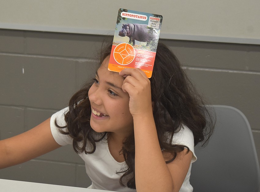Aubrey Vaca, a rising fifth grader at Lake Manatee K-8, asks questions to help identify what animal is on her card. The questions include whether it lives onland or in the water, and what color it is.