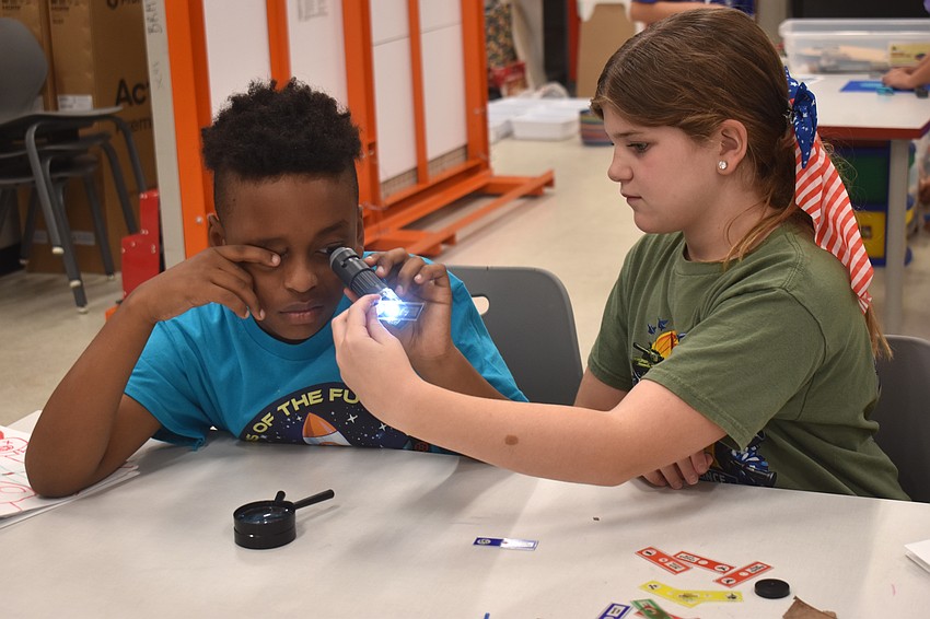 Matthew Sharlot, a rising eighth grader at Braden River Middle School, gets an extra hand from Ellie Rimer, a rising sixth grader at Braden River Middle School, in order to get a good look at a goldfish scale.