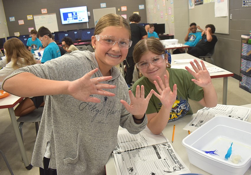 Aria Volpe, a rising sixth grader at Woodland Academy, and Ellie Rimer, a rising sixth grader at Braden River Middle School, say their hands are slimy and wet due to cleaning their feathers as part of the oil-spill activity.
