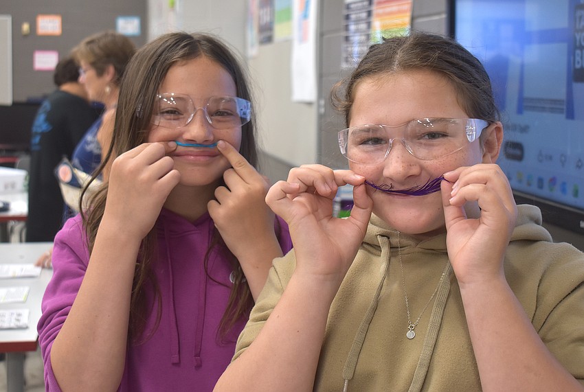 Addison Delazzer, a rising fifth grader at Braden River Elementary School, and Francesca Scafario, a rising sixth grader at Braden River Middle School, make their feathers into mustaches after they are all clean from oil.