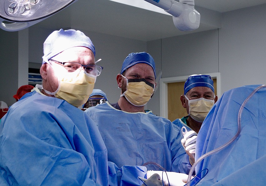 During his first week at Orlando Health — Health Central Hospital, Jacob Cox, center, was surprised to perform surgery with his father, Kevin Cox, left, and his grandfather, William Cox, right.