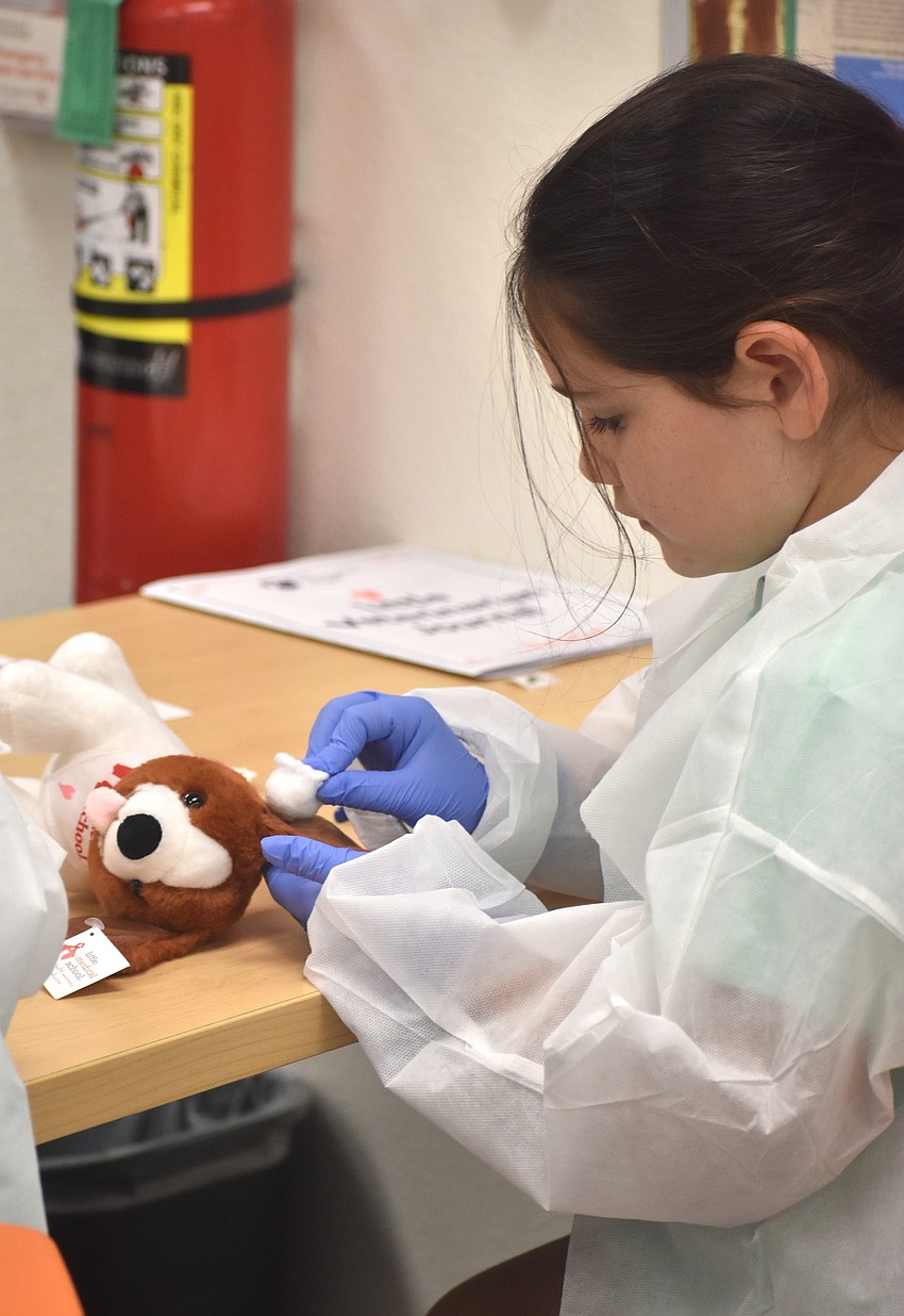 Isabelle Robinson, a rising third grader at Rowlett Elementary Academy, practices cleaning the ear of her dog with a cotton ball at the Little Vet School camp held at The Out-of-Door Academy.
