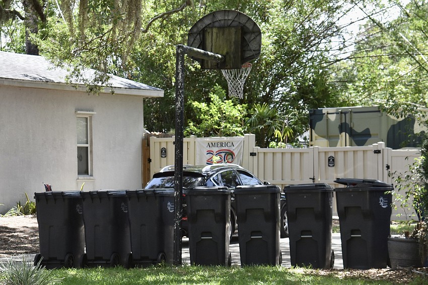 A row of seven garbage bins offers a hint that the house is not occupied by a single family.