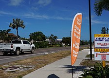 A feather banner is anchored next to the sidewalk on Gulf of Mexico Drive. Longboat Key staff are preparing an amendment that could prohibit that type of sign by refining the definition of flag in town code.