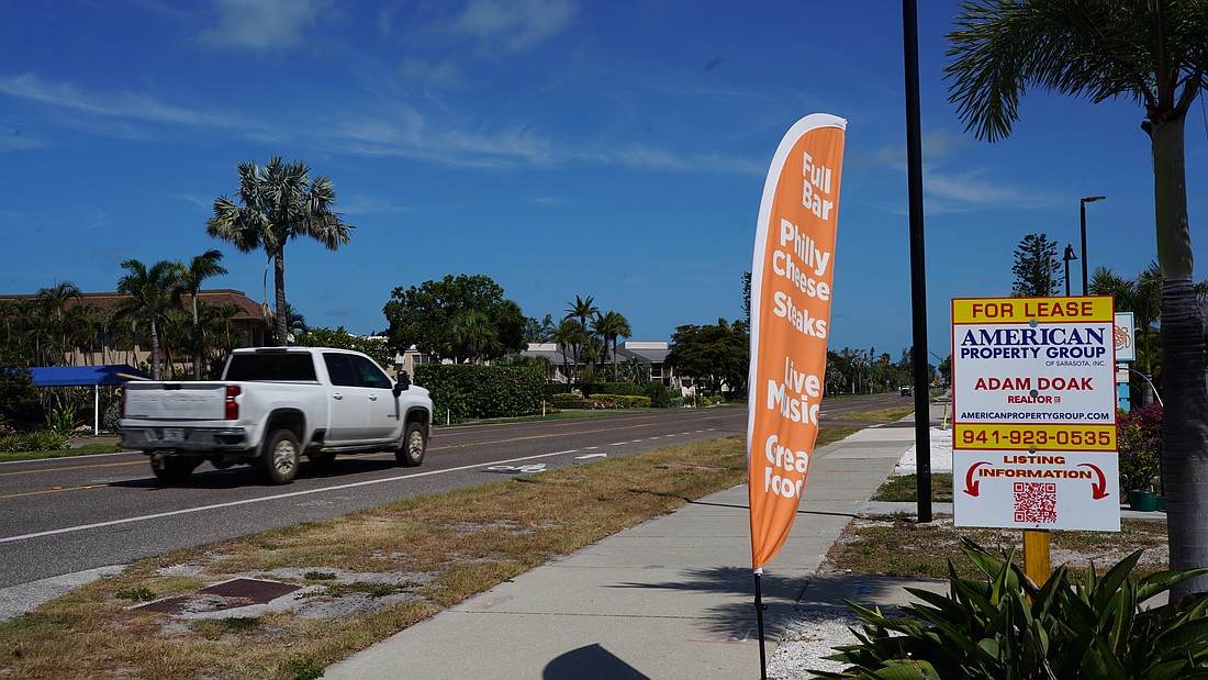A feather banner is anchored next to the sidewalk on Gulf of Mexico Drive. Longboat Key staff are preparing an amendment that could prohibit that type of sign by refining the definition of flag in town code.