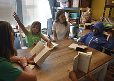 Teacher Erin Foss reads at a table that includes second grader Landry Shorb, Alison Rini visits and third grader Adonis Harris at Star Lab.