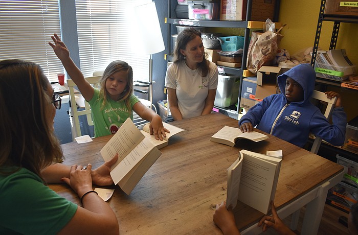 Teacher Erin Foss reads at a table that includes second grader Landry Shorb, Alison Rini visits and third grader Adonis Harris at Star Lab.