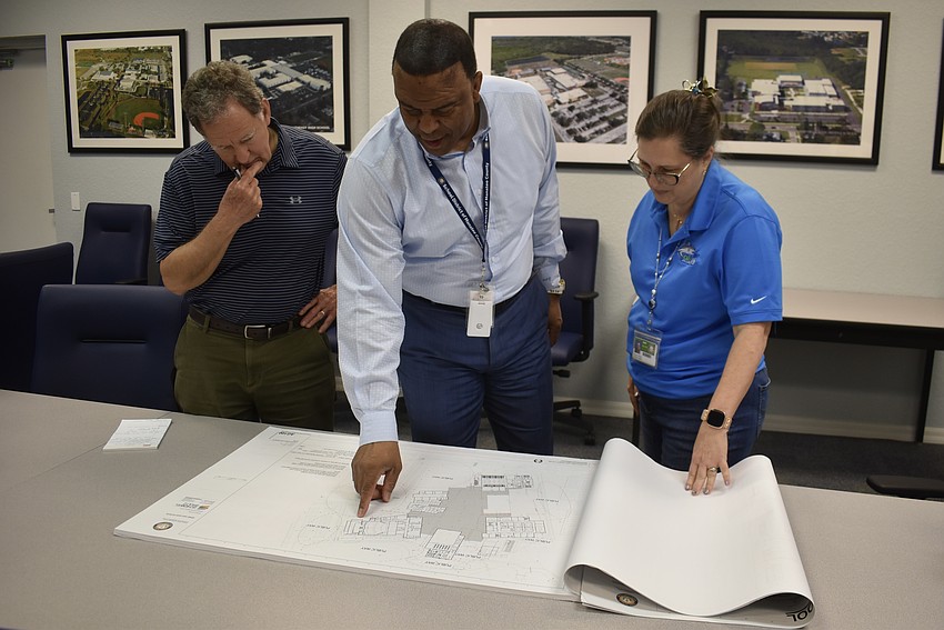 Project managers David Wiles and Michelle Begue stand on either side of Reginald L. Goff, Sr. looking at plans for Rangeland High School. Goff is the director of the Construction Services Department for the School District of Manatee County.