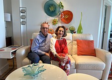 Jerome and Kathryn Chesley pose in their living room surrounded by colorful glass art that they've collected over the years.