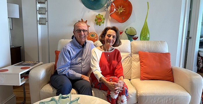 Jerome and Kathryn Chesley pose in their living room surrounded by colorful glass art that they've collected over the years.