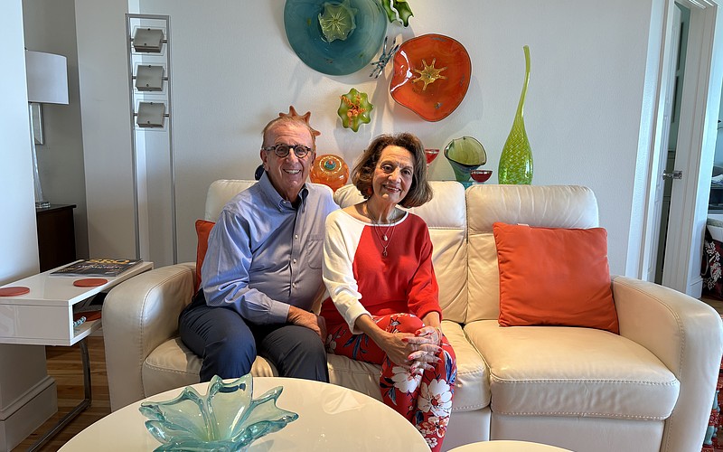 Jerome and Kathryn Chesley pose in their living room surrounded by colorful glass art that they've collected over the years.