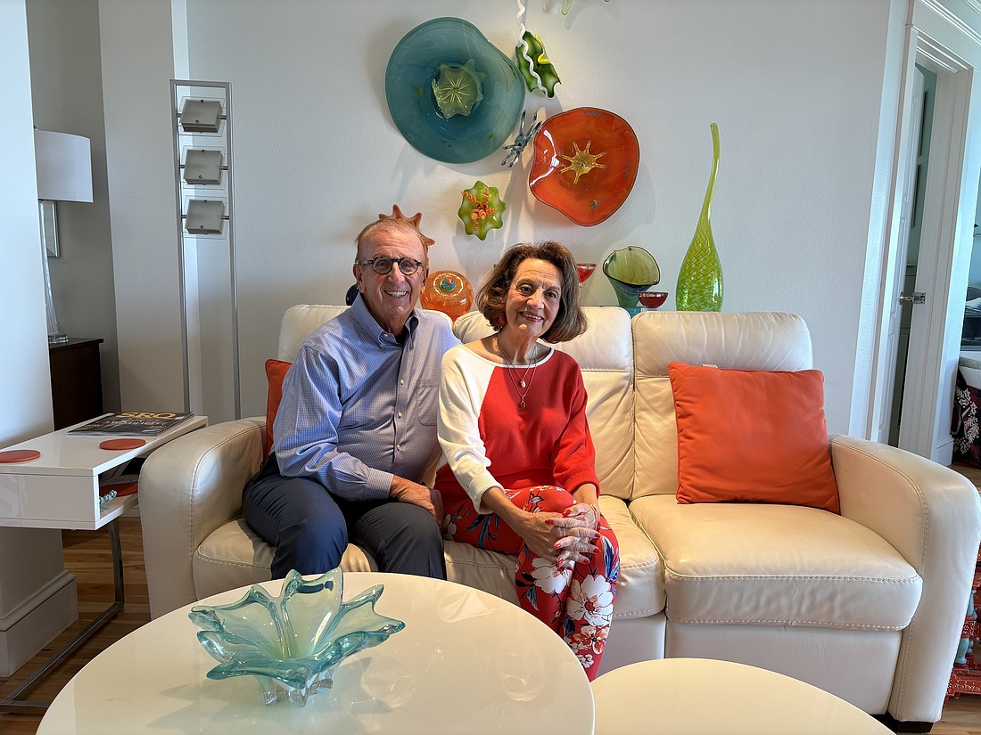 Jerome and Kathryn Chesley pose in their living room surrounded by colorful glass art that they've collected over the years.