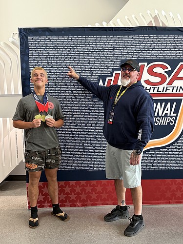 Flagler Palm Coast High School's Jackson Fedun (left) holds up his medals after winning the Youth 79 kg championship on June 22 at the USA Weightlifting National Championships in Colorado Springs as FPC coach Duane Hagstrom points to Fedun's name. Courtesy photo