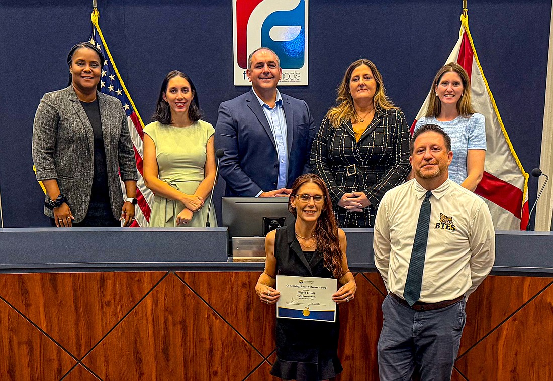Nicole Elliott (front row, left) was honored by the Flagler County School Board along with Kevin Blair, who couldn't attend the meeting, as Flagler Schools' Volunteers of the Year. Front row, right: Belle Terre Elementary School Assistant Principal Tim Ruddy. Back row: Superintendent LaShakia Moore and School Board members Christy Chong, Will Furry, Janie Ruddy and Lauren Ramirez. Courtesy photo.