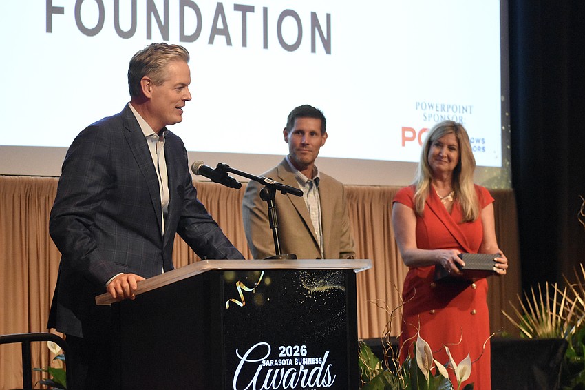 Phillip Lanham, president and CEO of Gulf Coast Community Foundation, recipient of the Community Impact Award, speaks as award presenter Eric Troyer of Kerkering Barberio & Co. Heather Kasten, president and CEO of the Greater Sarasota Chamber of Commerce, look on.
