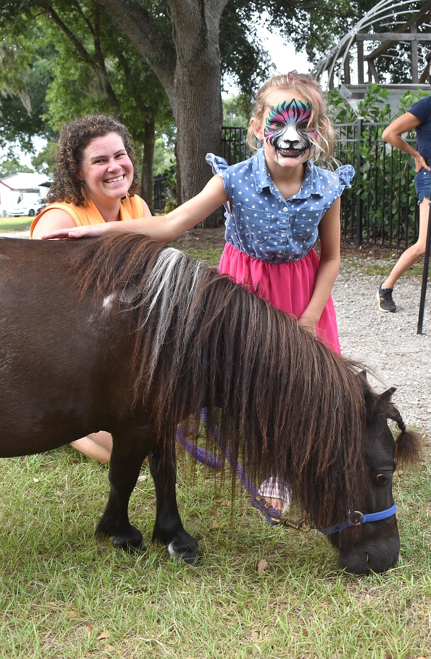 Jessica Whitmire, a board member at SMART with Heart, provides support as Sarasota's Cohen Taylor, 7, pets therapy pony, Penelope, at Fiorelli Winery.