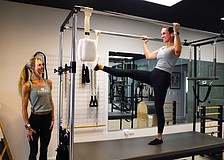 Paradise Pilates owner Julia Yesler, left, and Paulina Peralta, a certified personal trainer and Pilates instructor, demonstrate one of the stretches possible on the studio's new Cadillac reformer. Yesler recently opened the studio at The Centre Shops.