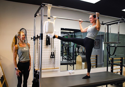 Paradise Pilates owner Julia Yesler, left, and Paulina Peralta, a certified personal trainer and Pilates instructor, demonstrate one of the stretches possible on the studio's new Cadillac reformer. Yesler recently opened the studio at The Centre Shops.