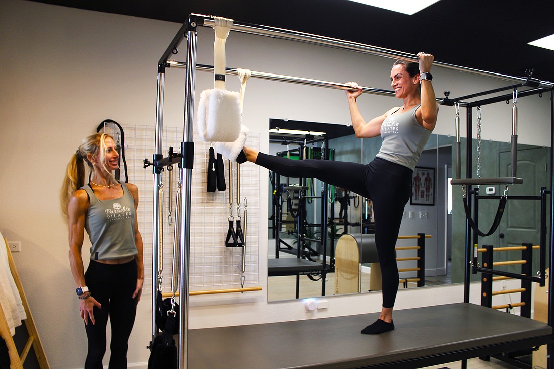 Paradise Pilates owner Julia Yesler, left, and Paulina Peralta, a certified personal trainer and Pilates instructor, demonstrate one of the stretches possible on the studio's new Cadillac reformer. Yesler recently opened the studio at The Centre Shops.