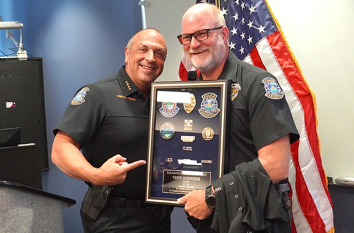 Sarasota Police Chief Rex Troche presents Officer William "Tripp" Schwenk with his framed badge during his June 26 retirement ceremony.