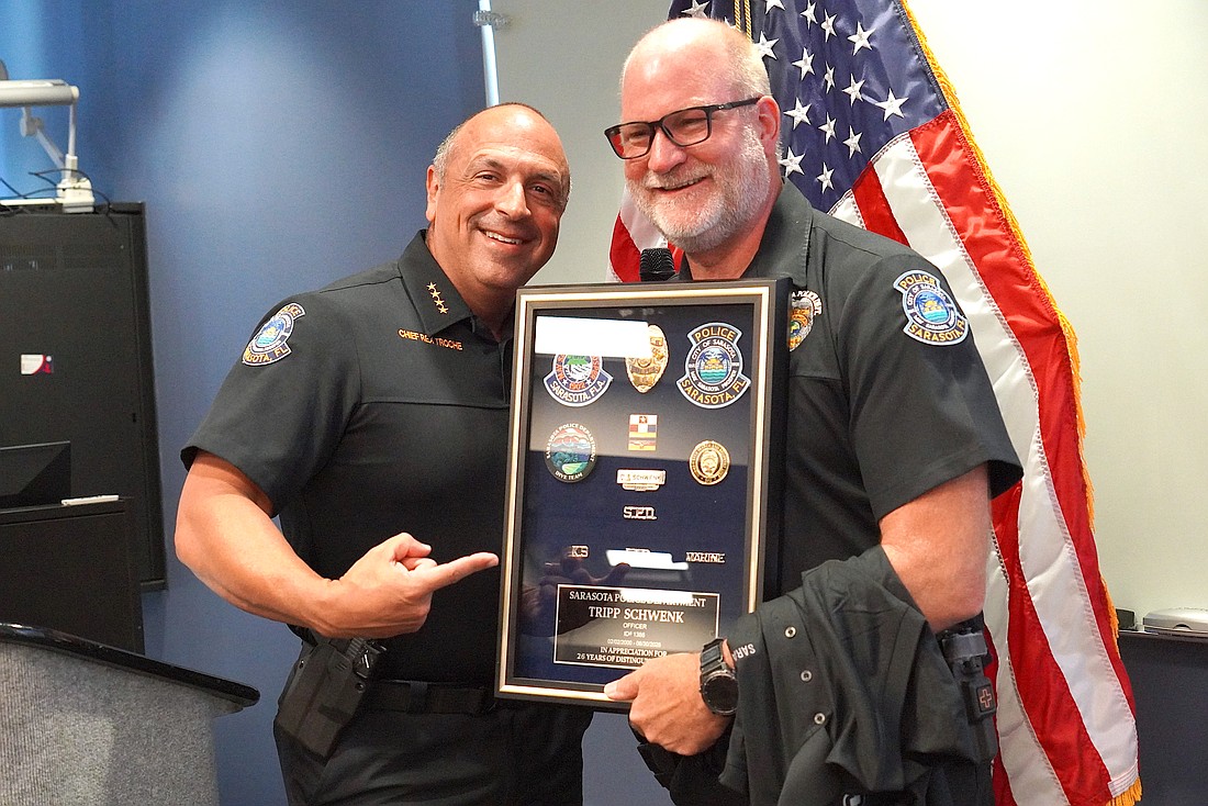 Sarasota Police Chief Rex Troche presents Officer William "Tripp" Schwenk with his framed badge during his June 26 retirement ceremony.