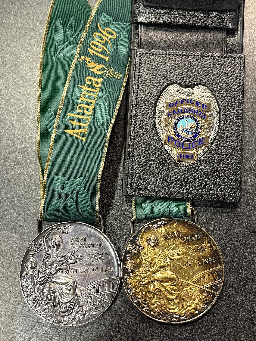 Officer Tripp Schwenk's gold and silver medals from the 1996 Olympics and a retirement replica of the badge he wore for 26 years.
