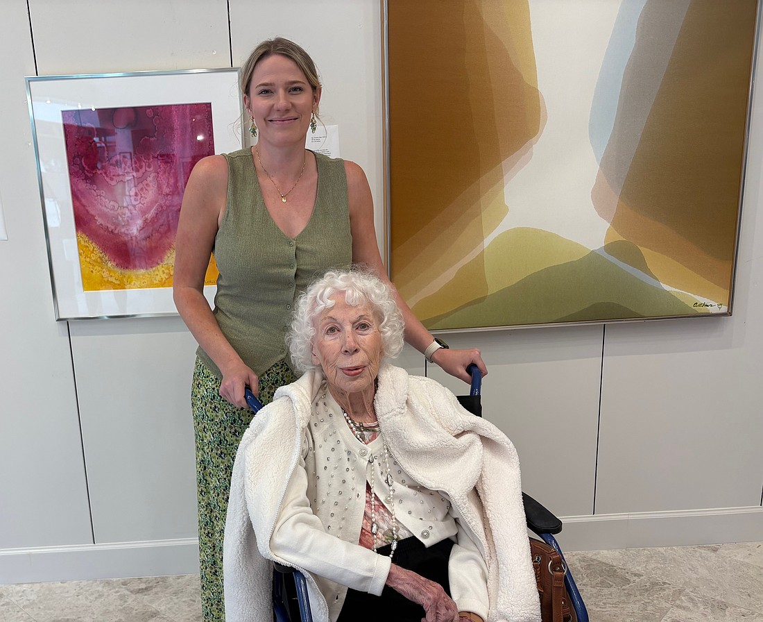 Beth Arthur poses with her granddaughter Sandy Arthur in front of two paintings acquired by Arts Advocates Gallery, "Bryce Canyon" (left) and "Sky Dreams."