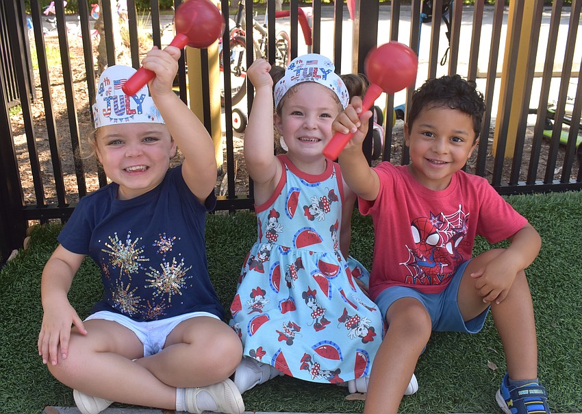 Three-year-olds Isabella Gonsalves, Emersyn Baker and Asher Lewis warm up for the bike parade at Kiddie Academy of Lakewood Ranch by making music with maracas.