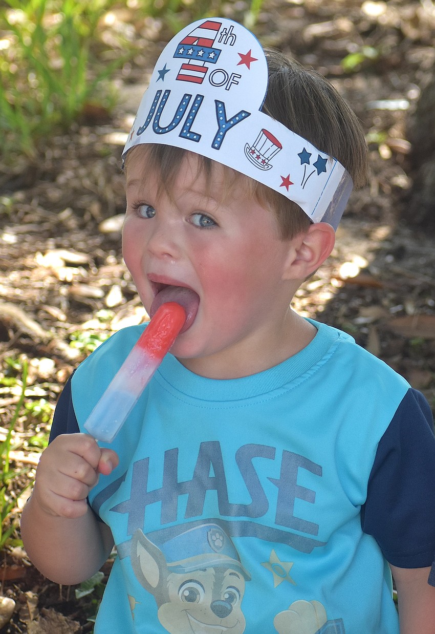 Dean Taylor, 2, takes a break from riding his scooter to cool down with a red, white and blue popsicle.