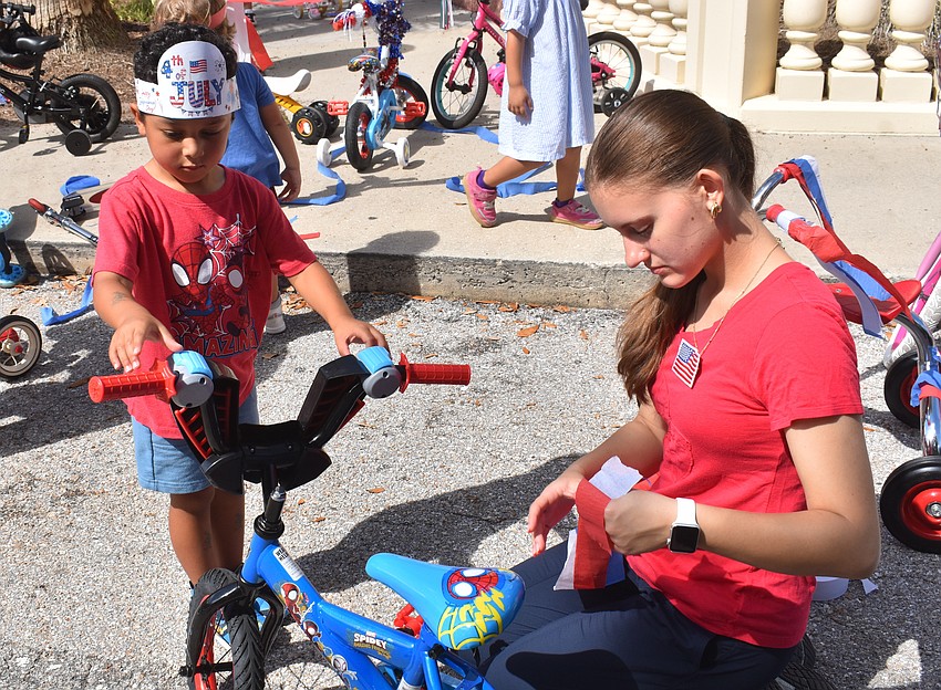 Asher Lewis, 3, gets help decorating his Spider-Man bike from Assistant Teacher Melissa Vendramini.