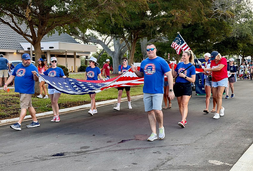 Members of the Observer Media Group carry a large-scale flag at Freedom Fest.