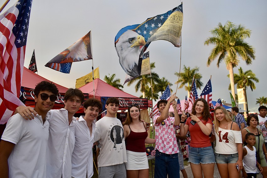 A group of local and out-of-town rowers walk through the park waving a huge flag.