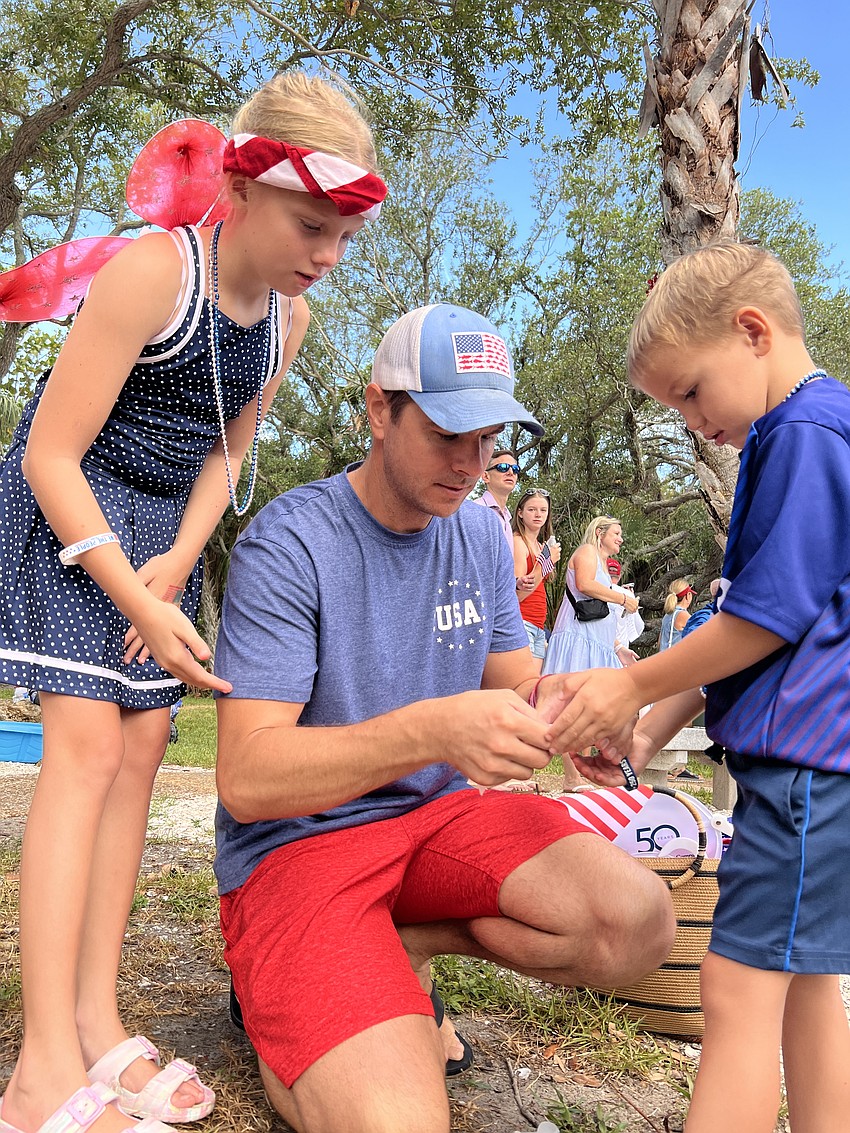 Austin, Ryan and Kent Theuer work to release a monarch butterfly during the butterfly release at Freedom Fest.