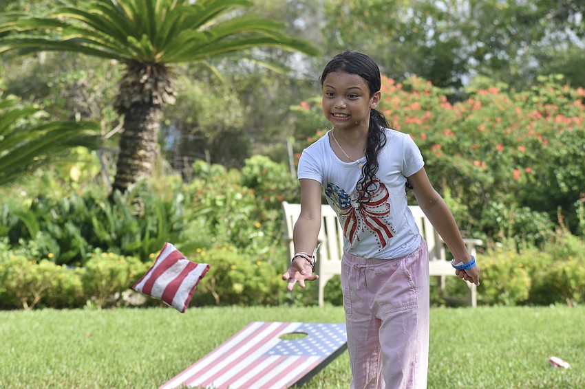 Vanessa Palfavi, 8, tosses a bean bag in a game of cornhole.