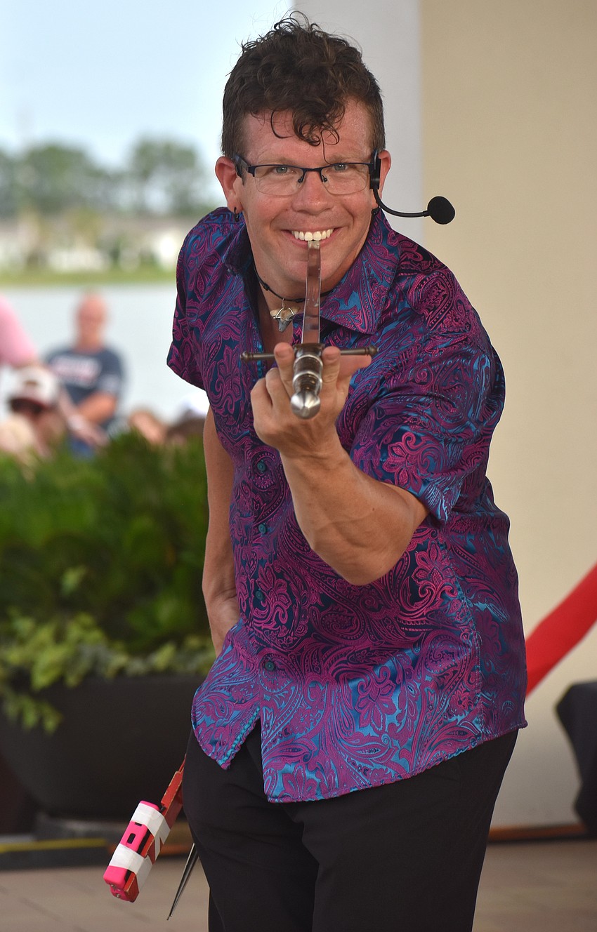 Noah Royak, a comedian and entertainer who has been at it for 12 years, eats a sword as part of his act at the Star-Spangled Spectacular at Waterside Place.