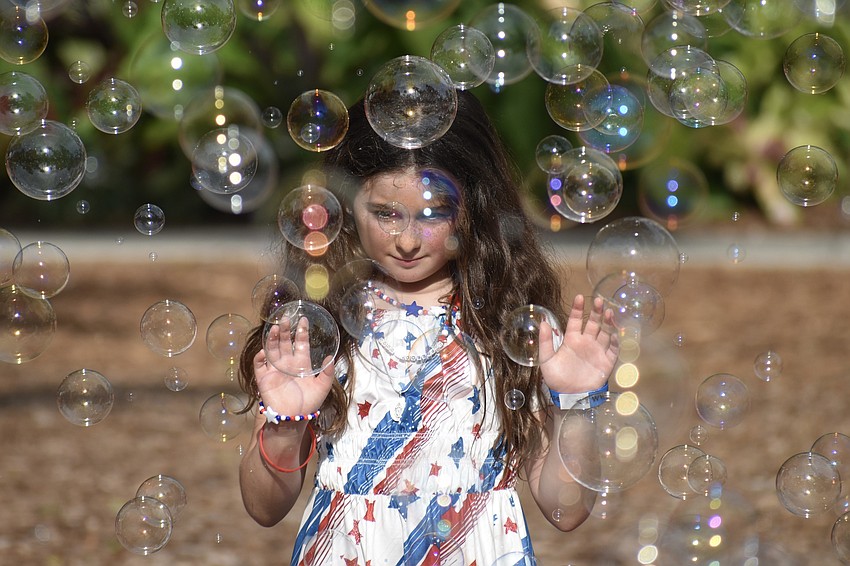 Annalise McLaughlin, 9, reaches out as a series of small bubbles rains down.