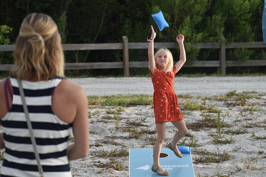 Tiffany Hymel and her daughter Alona Hymel, 6, play cornhole in the VIP and sponsors area.