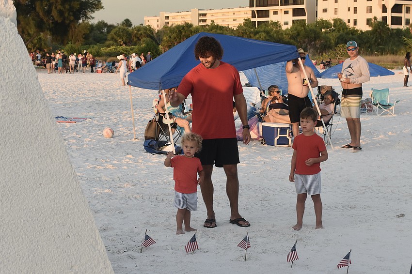 Otto Worden, 2, his father Kyle Worder, and brother Lincoln Worder, 5, look at a sand sculpture celebrating the country's 250th anniversary. His in-laws live in the area and the family travels there multiple times a year, watching the fireworks each year.