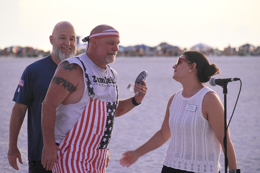 Mike Gatz stands beside Craig Merrill as he receives the award from Siesta Key Chamber of Commerce CEO Sarah Firstenberger.
