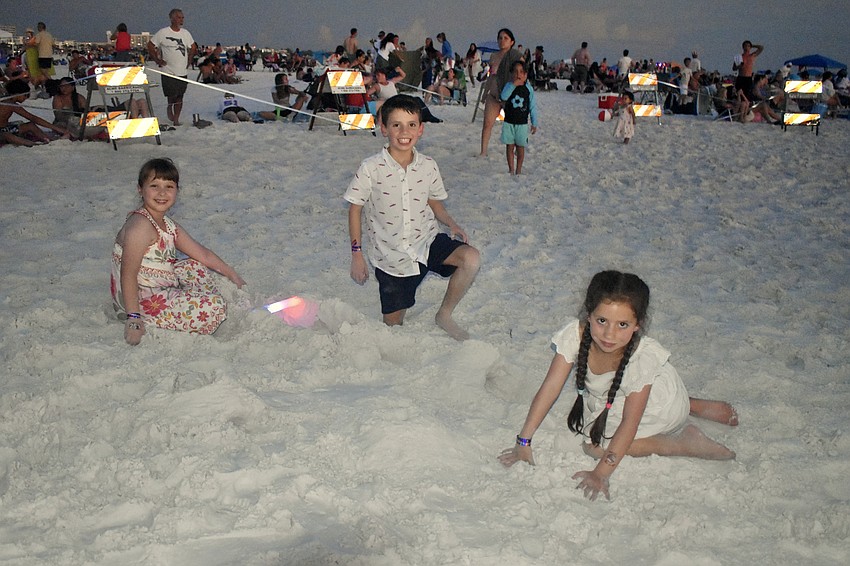 Luna Rodriguez, 8, Miguel Garcia, 9 and Beatriz Garcia, 7, play in the sand.